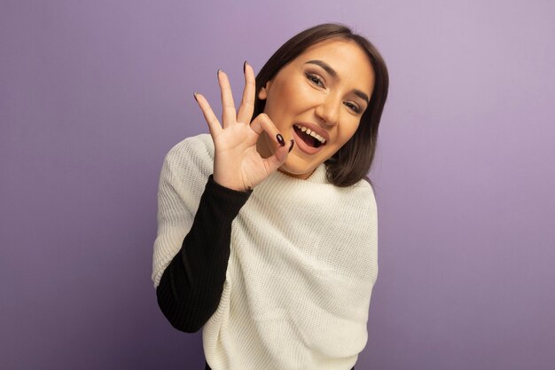 Jeune femme avec un foulard blanc souriant cher montrant signe ok