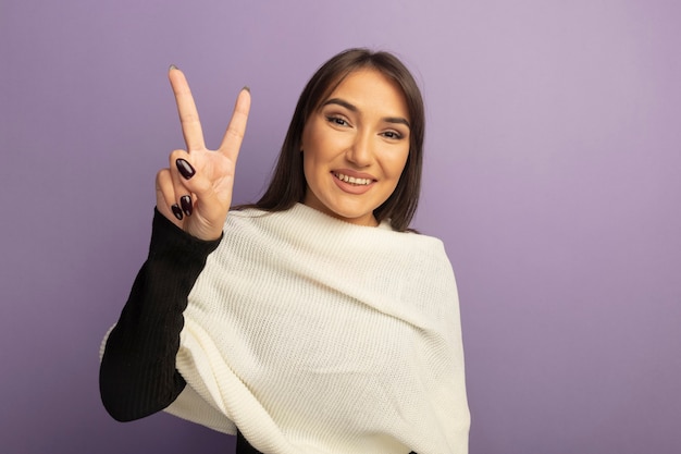 Jeune femme avec foulard blanc souriant joyeusement montrant v-sign