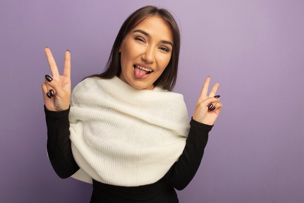 Jeune femme avec foulard blanc souriant joyeusement sticking out tongue