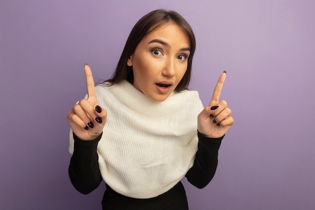 Jeune femme avec un foulard blanc souriant surpris montrant l'index