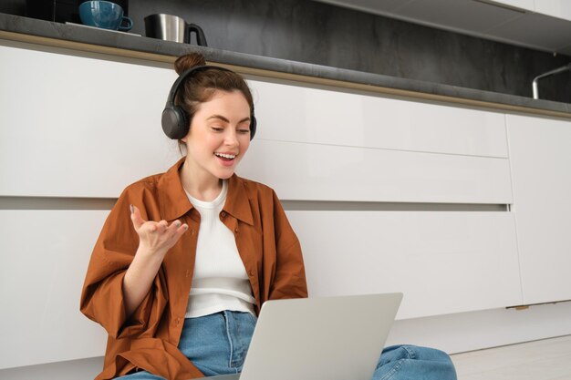 Une jeune femme freelance rejoint le chat en ligne une étudiante qui étudie à la maison est assise sur le sol avec un ordinateur portable et