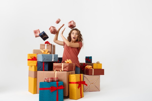 Jeune femme frisée surprise parmi les coffrets cadeaux couchés et tombants