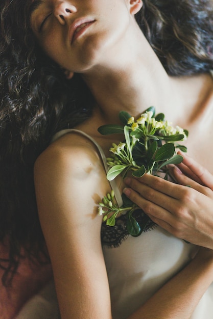 Photo gratuite jeune femme gardant des fleurs près de la poitrine