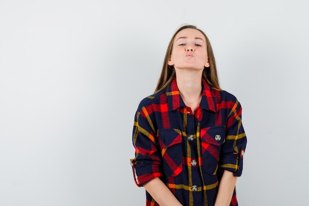 Jeune femme en gardant les lèvres pliées dans une chemise décontractée et à la belle. vue de face.