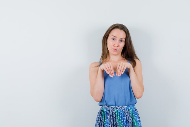 Jeune femme en gardant les mains comme les pattes sur la poitrine en maillot, jupe et à mignon