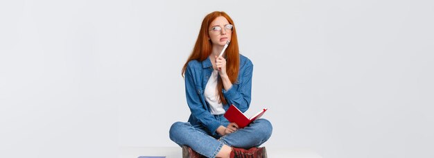 Jeune femme géniale réfléchie et créative concentrée avec des cheveux rouges dans des verres à la perplexité