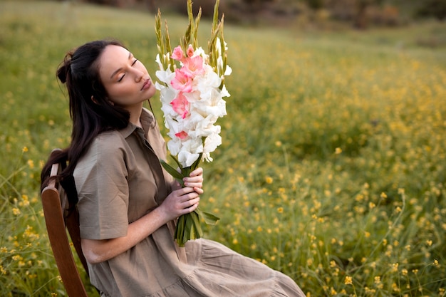 Photo gratuite jeune femme avec glaïeul dans la nature