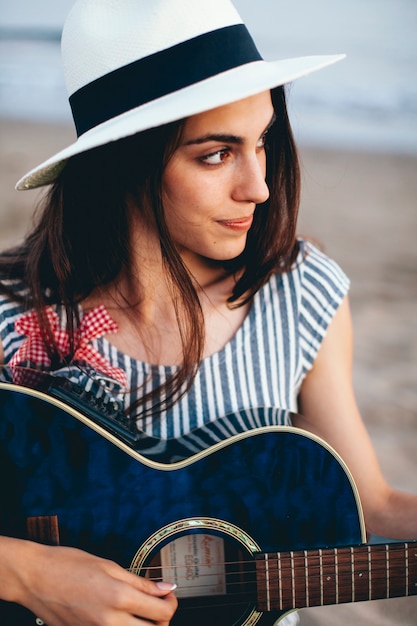 Jeune femme avec une guitare à la plage