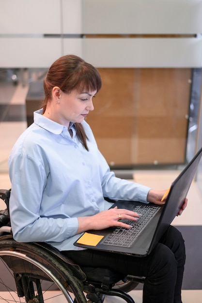 Jeune femme handicapée au bureau regardant un ordinateur portable