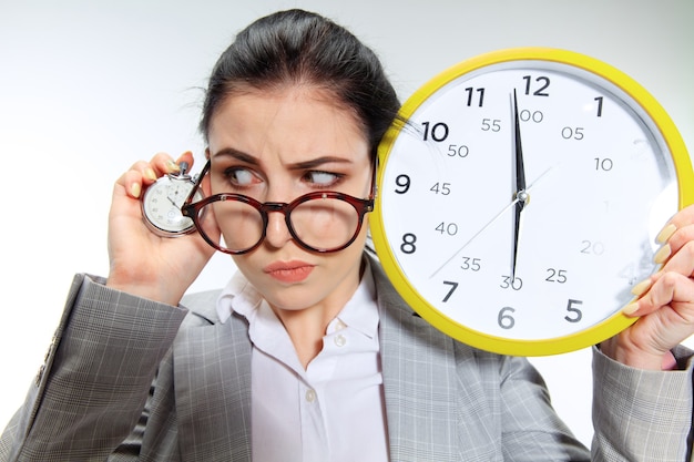 La jeune femme a hâte de rentrer chez elle après le bureau. Tenir l'horloge et attendre cinq minutes avant la fin.