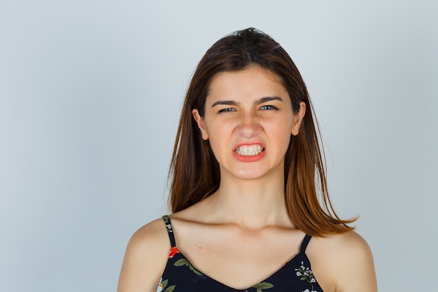 Jeune femme en haut floral montrant les dents et à la colère