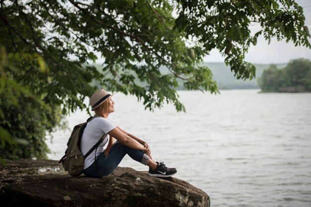 Jeune femme heureuse assise avec sac à dos profiter de la nature après la randonnée.