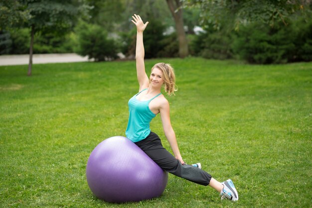 Jeune femme heureuse avec ballon de fitness, en plein air