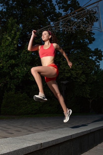 Photo gratuite jeune femme heureuse courant en plein air dans un parc de la ville. fille courir courir dans la nature pour perdre du poids et maintenir une vie saine. mode de vie sain