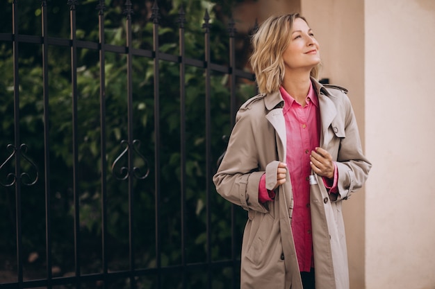 Jeune femme heureuse en manteau de printemps dans la ville