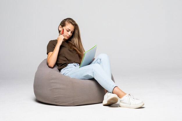 Jeune femme heureuse prend des notes dans le bloc-notes, isolé sur un mur blanc