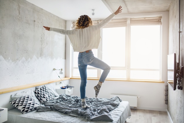 Photo gratuite jeune femme heureuse sautant sur le lit le matin
