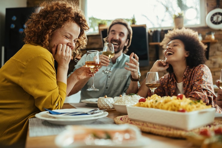 Photo gratuit jeune femme heureuse et ses amis s'amusant en buvant du vin pendant l'heure du déjeuner à la maison