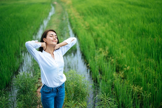 Jeune femme heureusement dans un champ vert à la journée ensoleillée