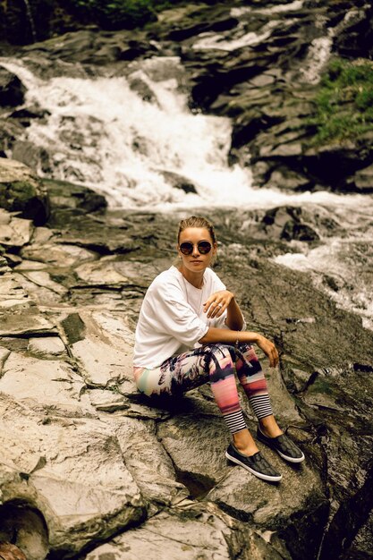 jeune femme hippie en leggings lumineux et lunettes rondes dans la nature