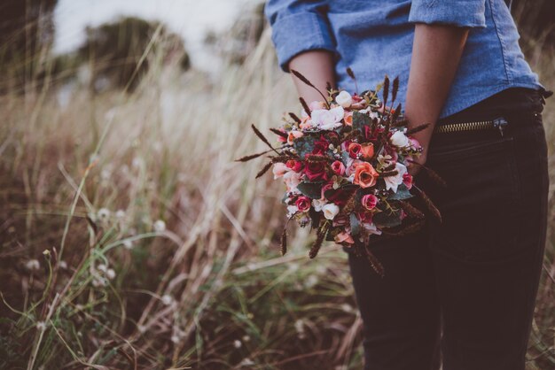 Jeune femme hipster tenant bouquet de roses tout en profitant de la marche au terrain de l&#39;été.