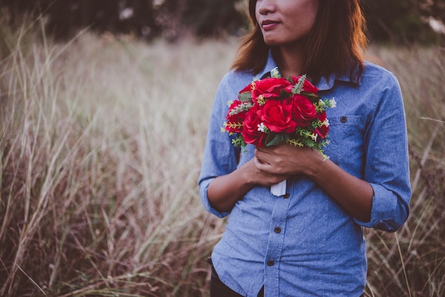 Jeune femme hipster tenant bouquet de roses tout en profitant de la marche au terrain de l&#39;été.