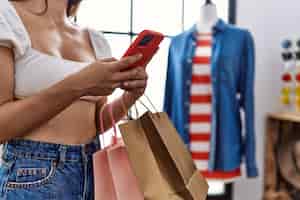 Photo gratuite jeune femme hispanique à l'aide de smartphone shopping au magasin de vêtements