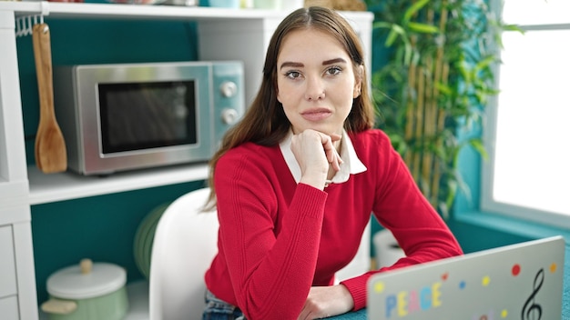 Jeune femme hispanique assise sur une table avec une expression détendue dans la salle à manger