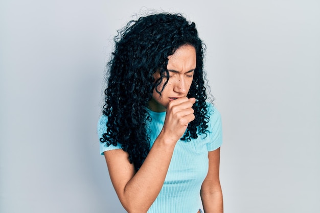 Photo gratuite jeune femme hispanique aux cheveux bouclés portant un t-shirt bleu décontracté se sentant mal et toussant comme symptôme du concept de soins de santé du rhume ou de la bronchite