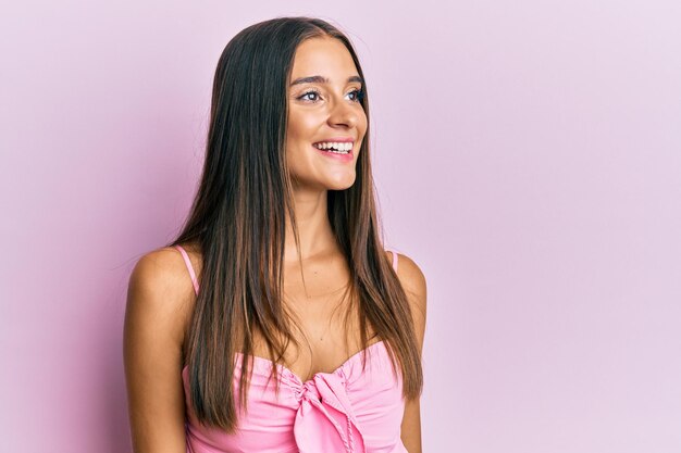 Jeune femme hispanique portant un style décontracté avec une chemise sans manches regardant de côté avec un sourire sur le visage, une expression naturelle. rire confiant.