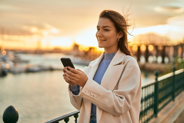 Jeune femme hispanique souriante heureuse utilisant un smartphone dans la ville