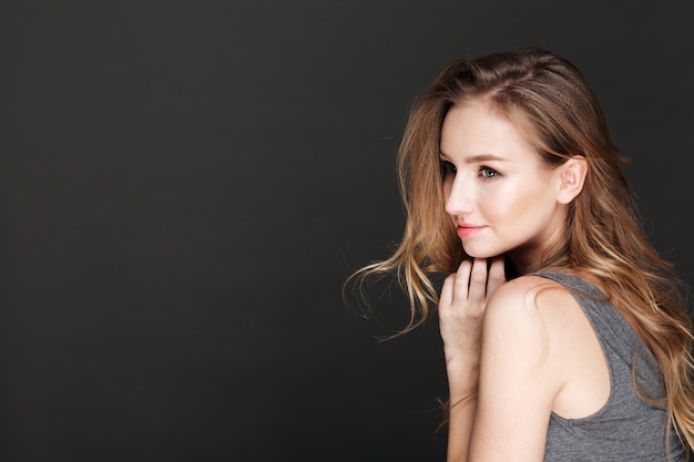 Jeune femme incroyable posant sur un mur sombre