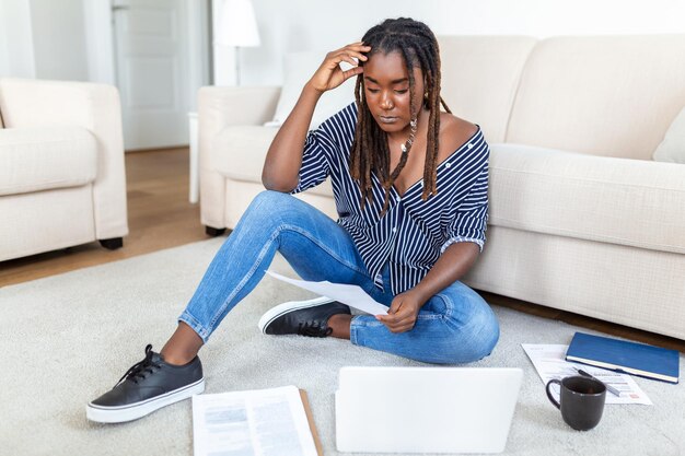 Jeune femme indépendante positive regardant une vidéo sur un blog sur netbook et prenant un café dans une maison confortable Belle jeune femme d'affaires travaillant sur un ordinateur portableFreelancer se connectant à internet