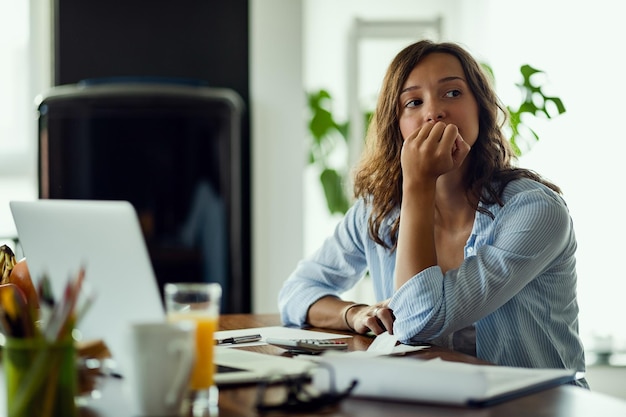 Jeune femme inquiète pensant à quelque chose en calculant son budget domestique