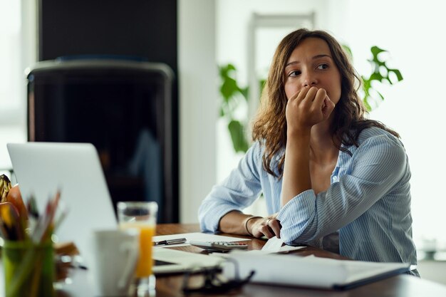 Jeune femme inquiète pensant à quelque chose en calculant son budget domestique