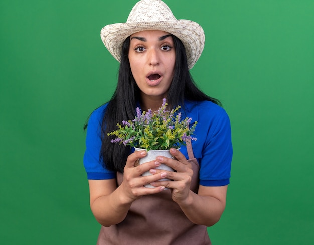 Jeune femme de jardinier caucasienne en uniforme et chapeau tenant un pot de fleurs