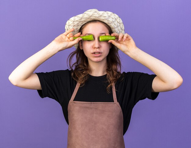 Jeune femme jardinier portant un chapeau de jardinage mettant le poivre cassé sur les yeux