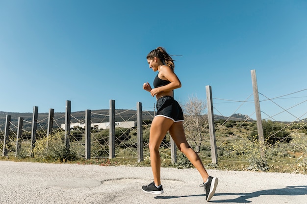 Jeune femme jogging le long d&#39;une route de campagne