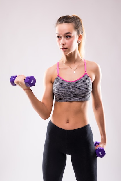 Jeune femme jolie fille fitness faire différents exercices d'aérobic musculaire avec des haltères sur blanc habillé en vêtements de sport