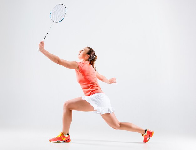 Jeune femme jouant au badminton sur blanc