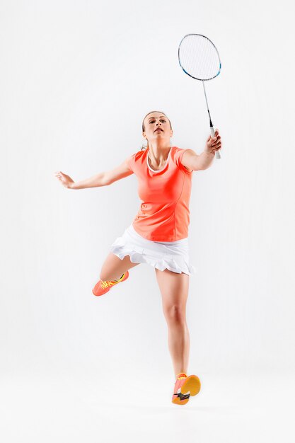 Jeune femme jouant au badminton sur mur blanc