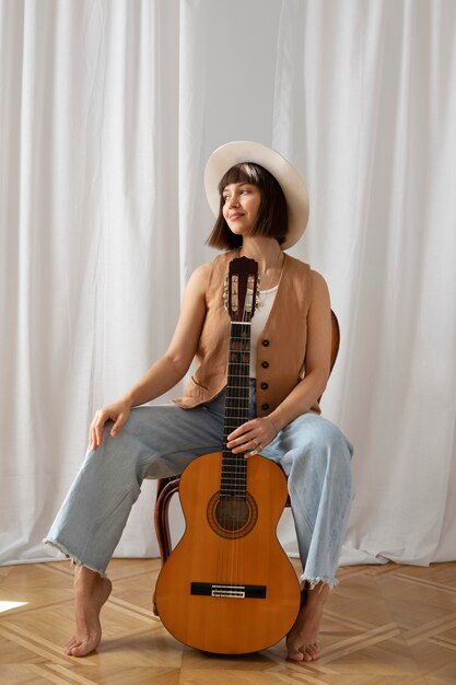 Jeune femme jouant de la guitare à l'intérieur