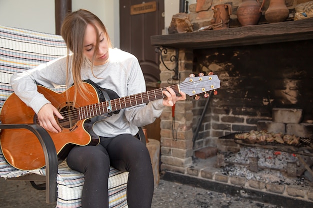 Une jeune femme joue de la guitare dans une ambiance feutrée. Le concept de passe-temps et de loisirs.