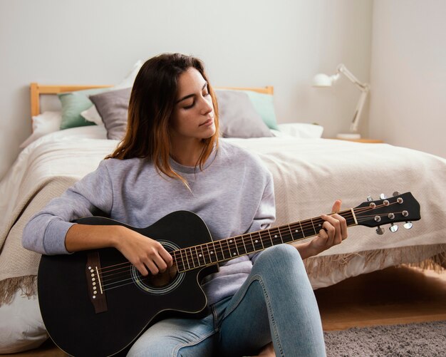 Jeune femme, jouer guitare, chez soi