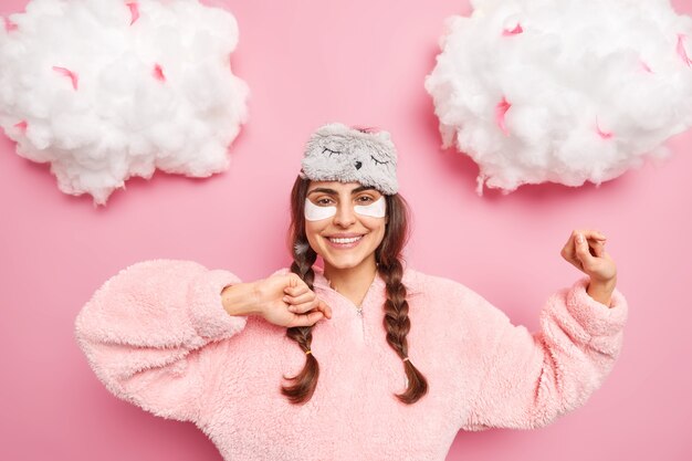 Une jeune femme joyeuse et insouciante danse avec les bras levés porte un pyjama