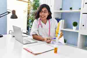 Photo gratuite jeune femme latine portant l'uniforme de médecin tenant un modèle anatomique du genou à la clinique