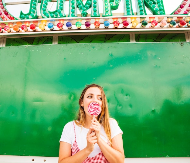 Jeune femme léchant sucette au parc d&#39;attractions