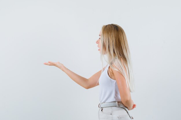Jeune femme levant la main de manière agressive en chemisier blanc et à la recherche concentrée.