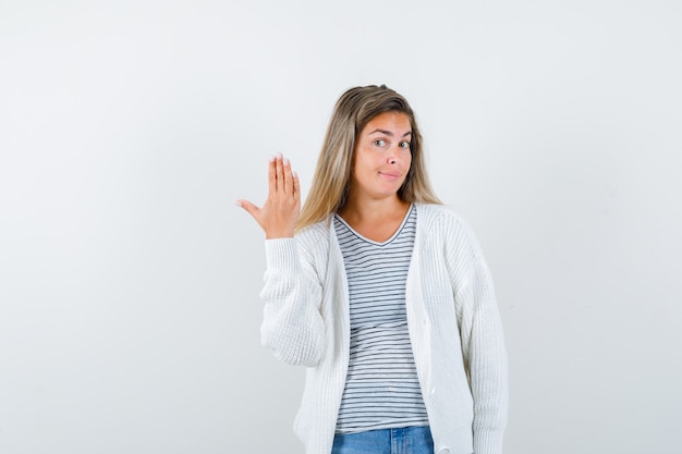 Jeune femme levant la main en t-shirt, veste et à la confiance. vue de face.