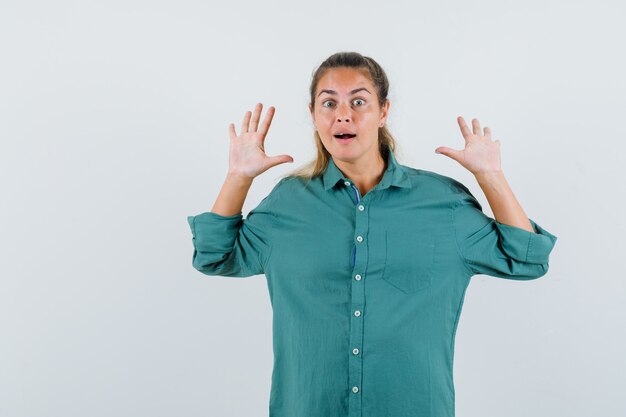 Jeune femme levant les mains pour défendre en chemise bleue et à la recherche d'anxiété